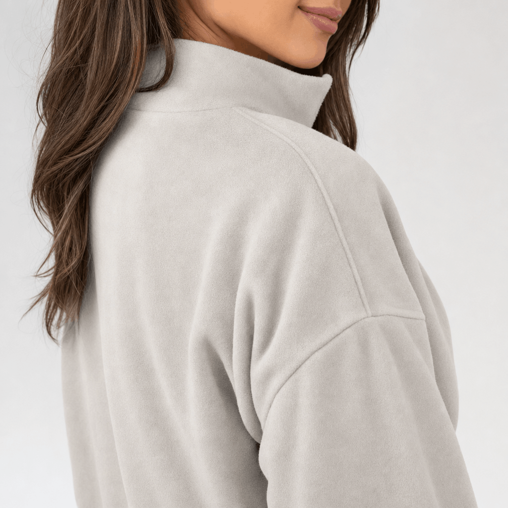 Close-up back and side view of a beige quarter-zip pullover, highlighting the raised collar and relaxed shoulder fit.