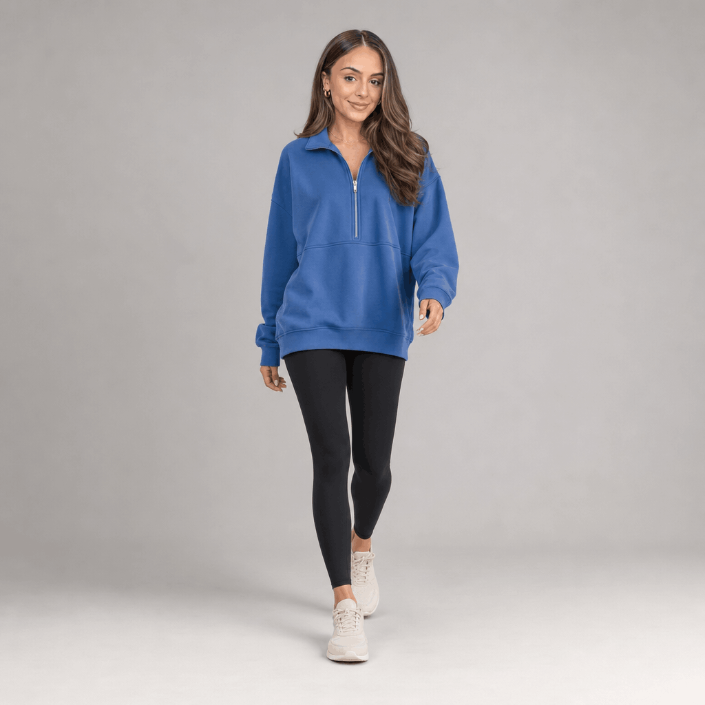 Full-body view of a female model wearing the bright blue quarter-zip pullover with black trousers.