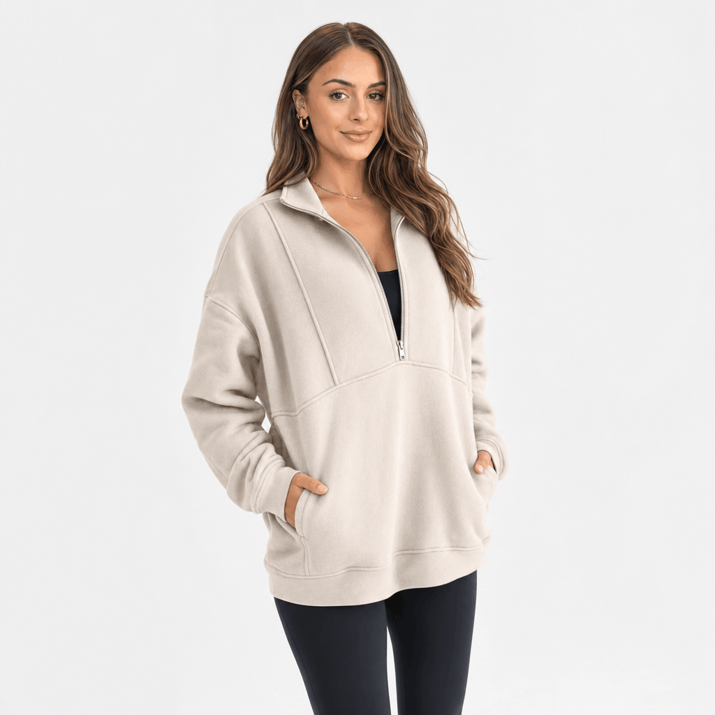 Female model wearing a beige quarter-zip pullover with black trousers.