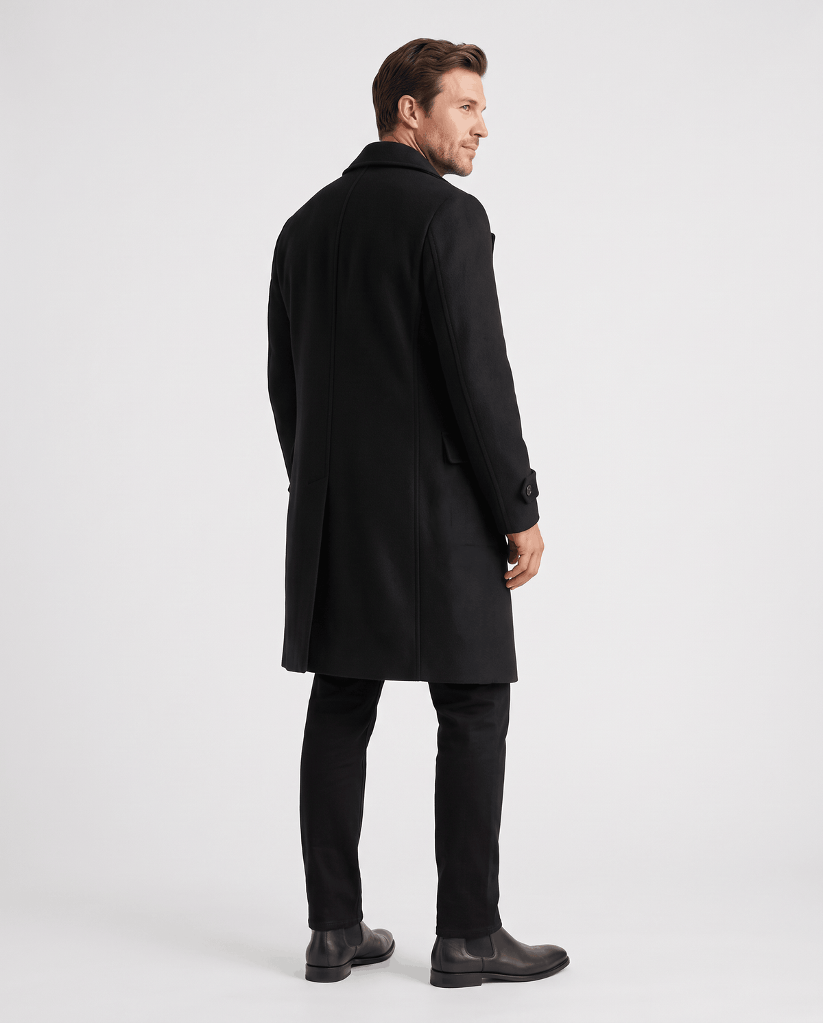 Back view of a long black wool coat worn with black trousers and boots