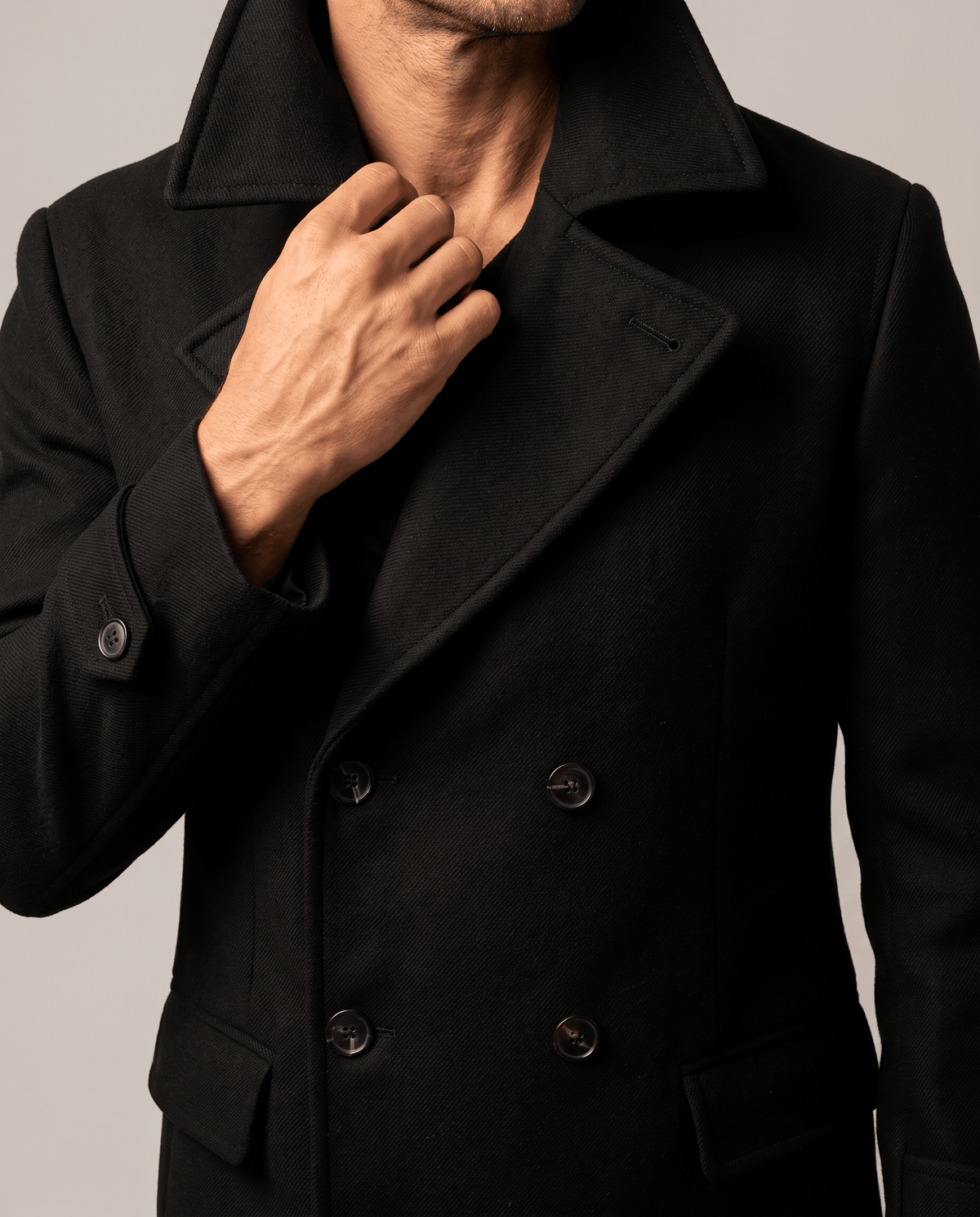 Close-up of black wool coat collar and lapel with a hand at the neckline