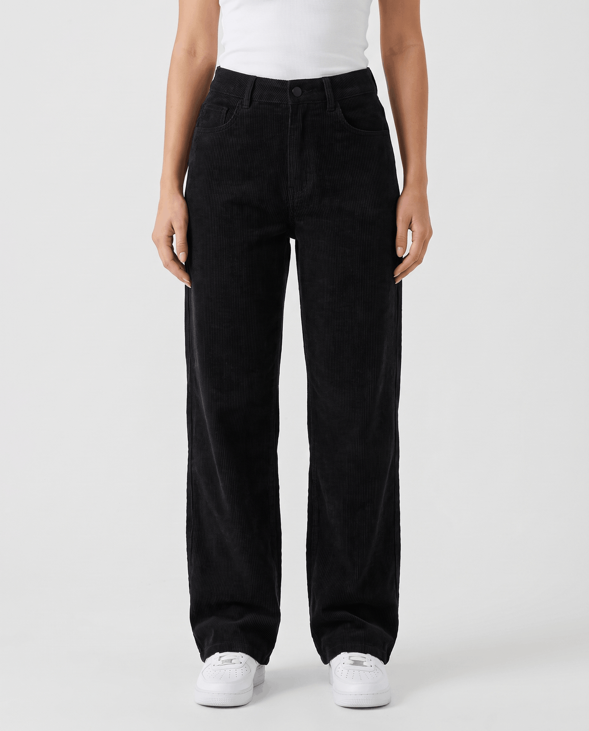 Front view of black high-rise ribbed trousers with a wide leg and white sneakers