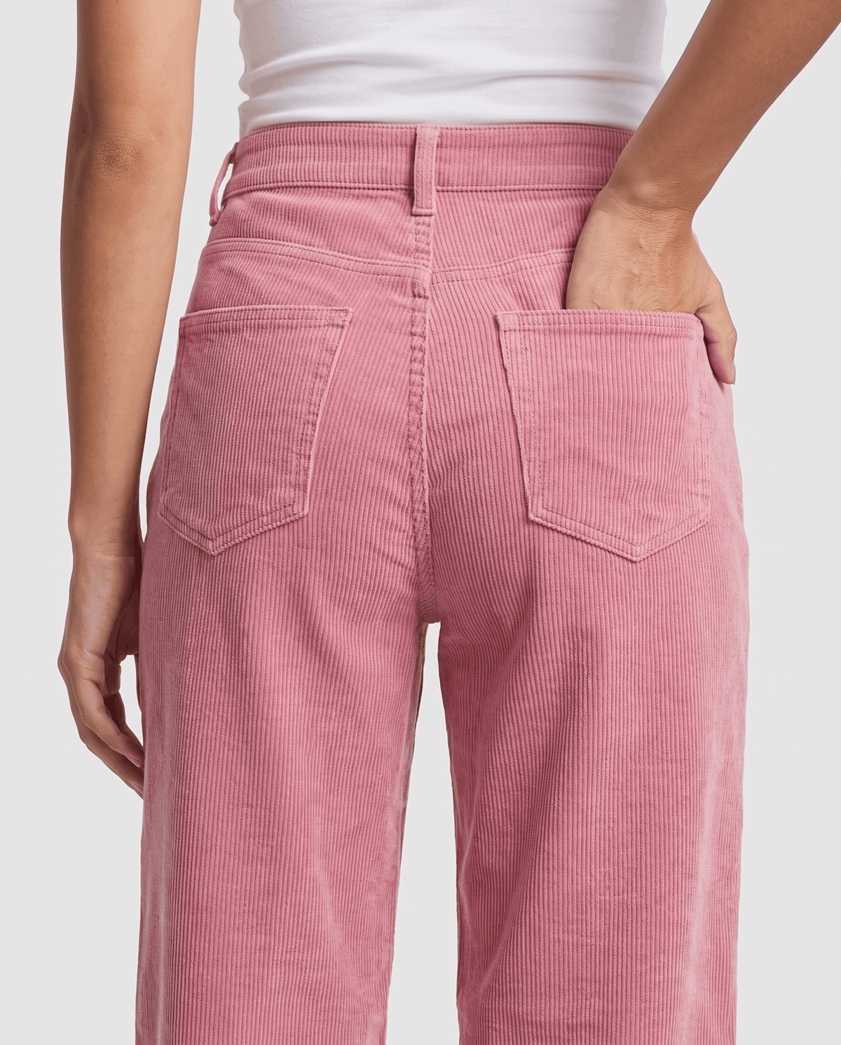 Close-up of a stitched back patch pocket on soft pink ribbed fabric