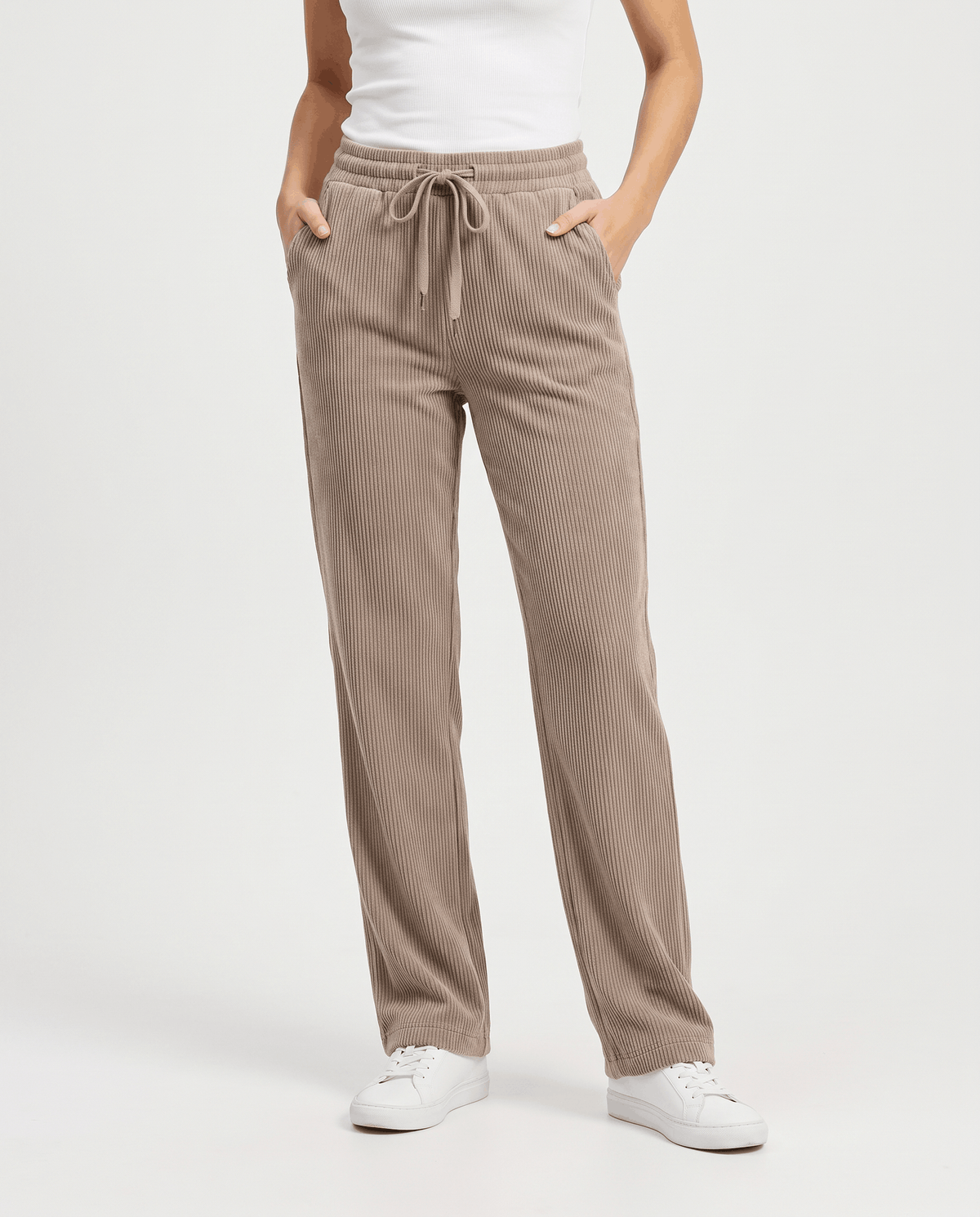 Three-quarter front view of taupe drawstring trousers with hands in the side pockets