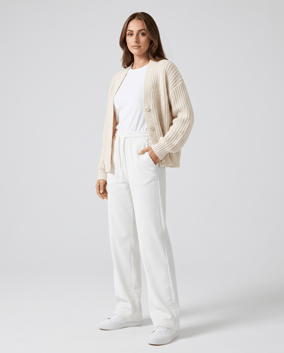Model in ivory ribbed trousers styled with a cream cardigan and white sneakers