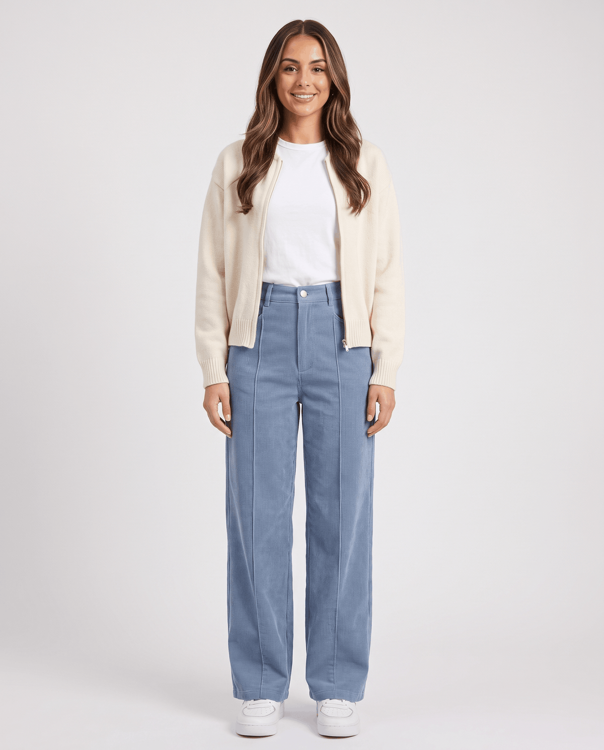 Smiling model in light blue wide-leg pants styled with a cream cardigan and white tee