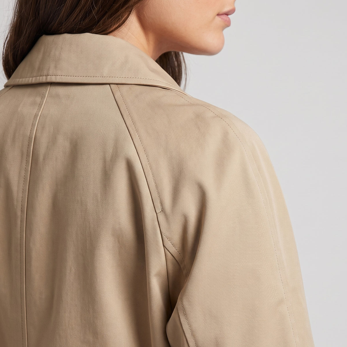 Rear shoulder close-up of khaki cotton coat showing the raglan sleeve seam and point collar