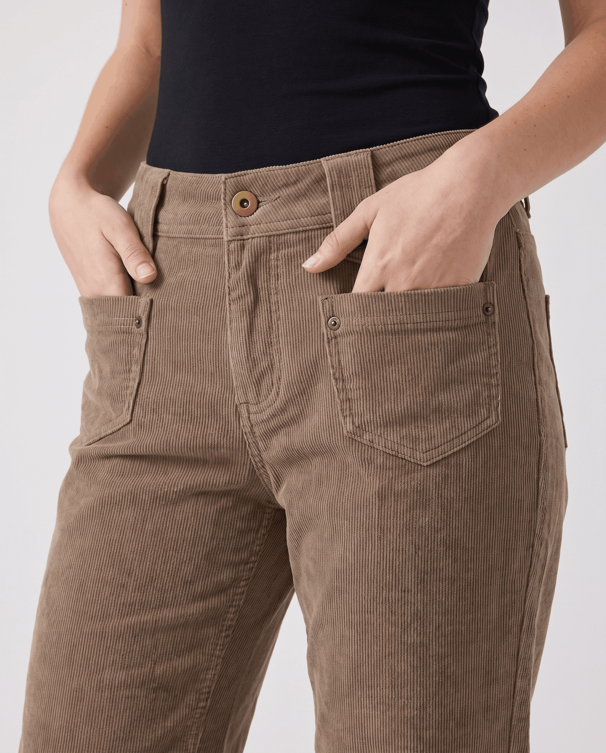Close-up of the zip fly, button waist and stitched front patch pockets with hands tucked in