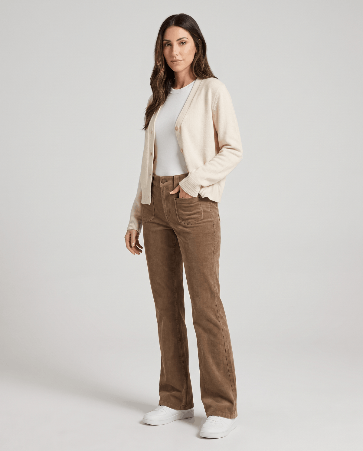 Model in khaki ribbed pants styled with a cream cardigan, white tee and white sneakers