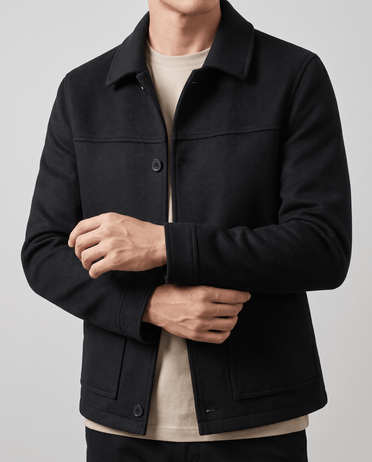 Black jacket front detail with the placket half undone over a light layer