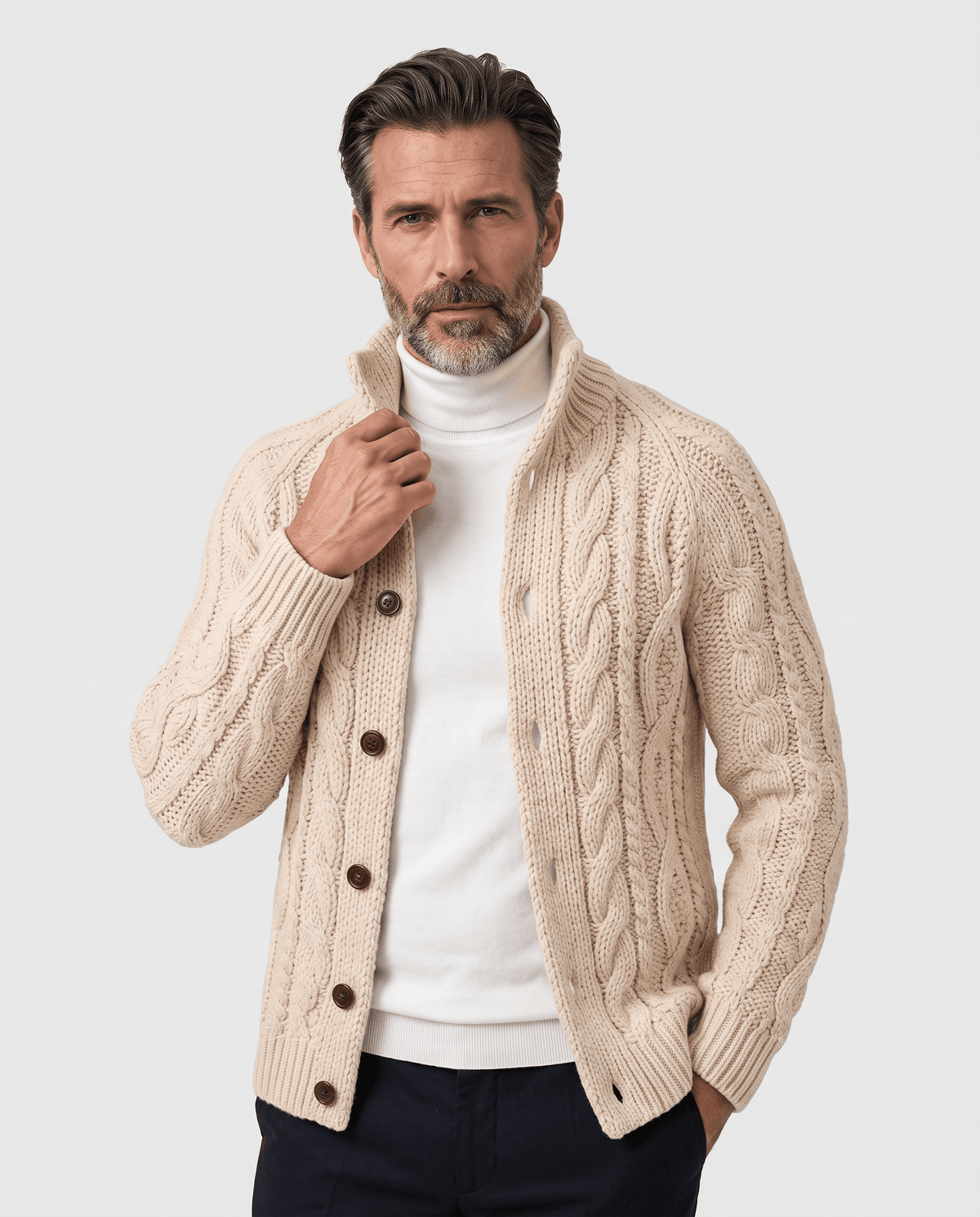 Men's beige cable knit cardigan with button front worn over a white turtleneck