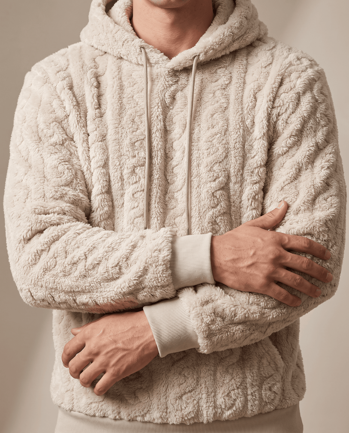 Off-white hoodie with arms crossed, showing the cable pattern and ribbed cuffs