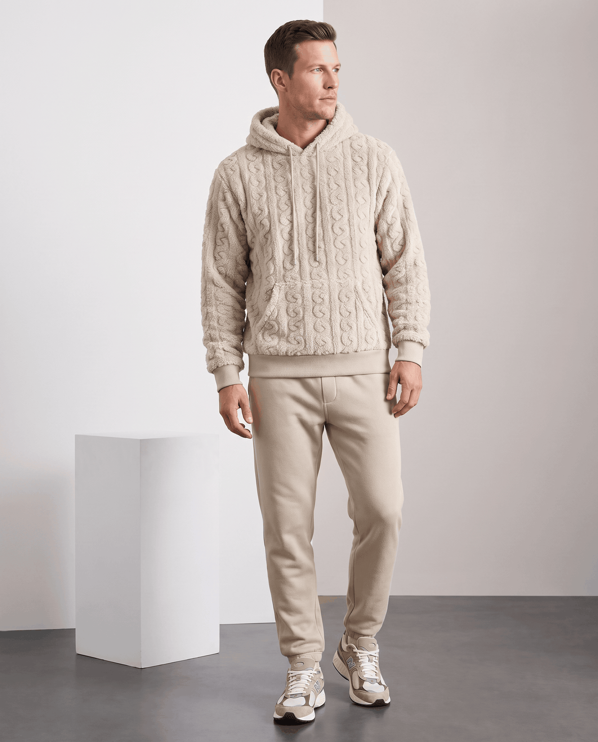 Full-length view of off-white hoodie styled with matching beige pants and sneakers