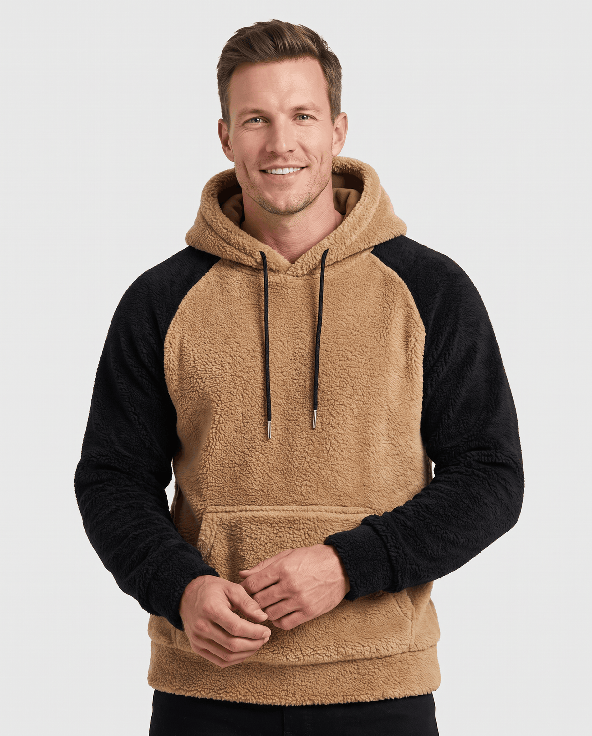 Front view of camel hoodie with black sleeves and hands resting in the front pocket