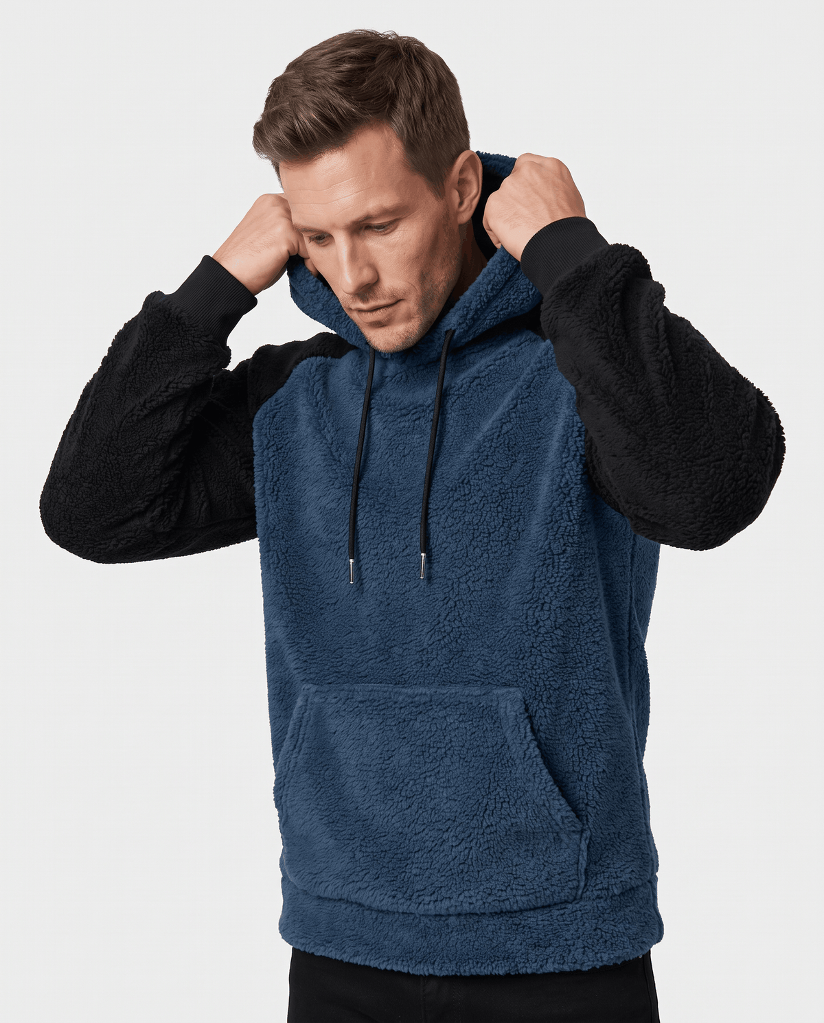 Navy blue hoodie with black sleeves worn with hands raised to the hood