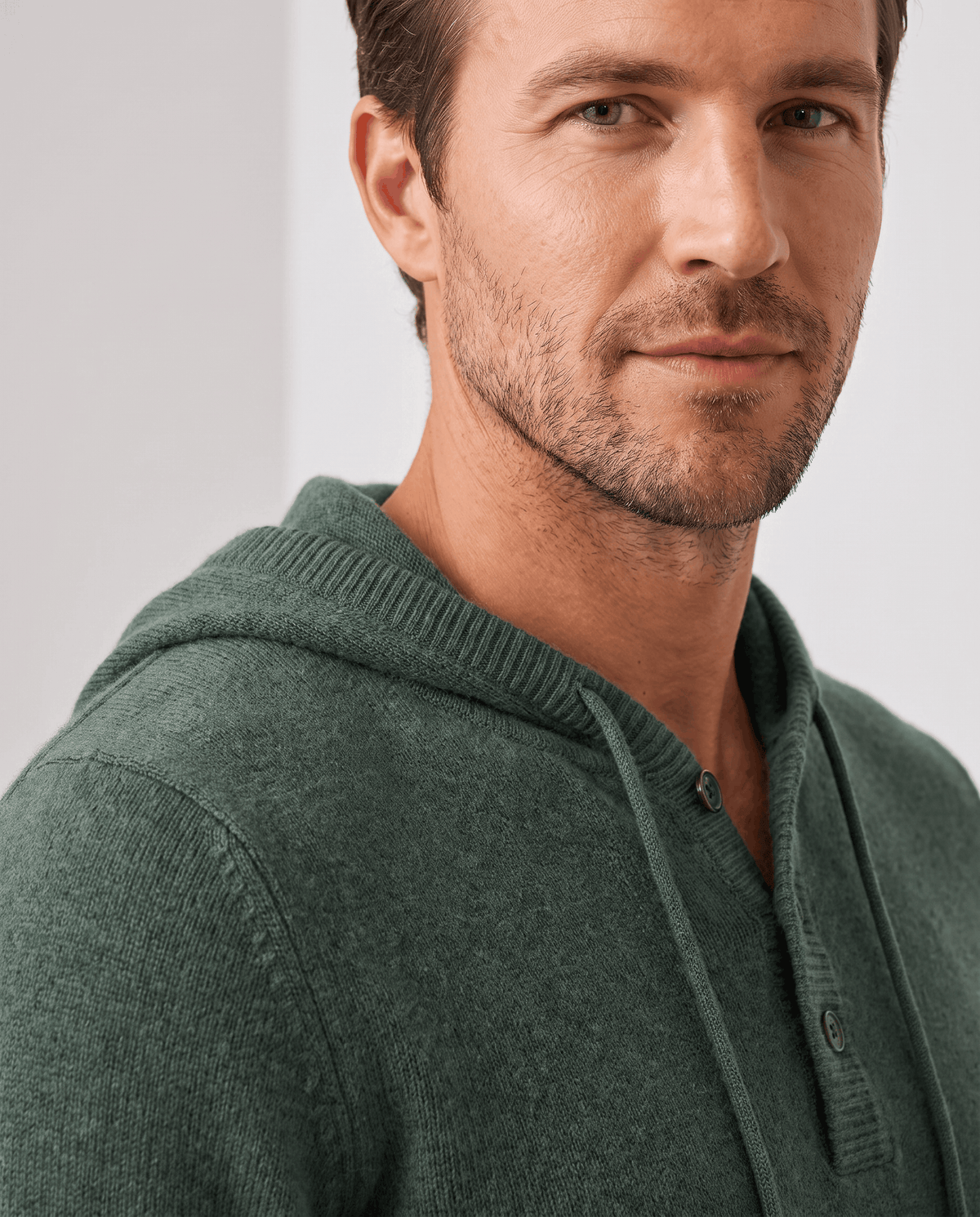 Close-up of a green hoodie neckline with three-button placket and drawcords