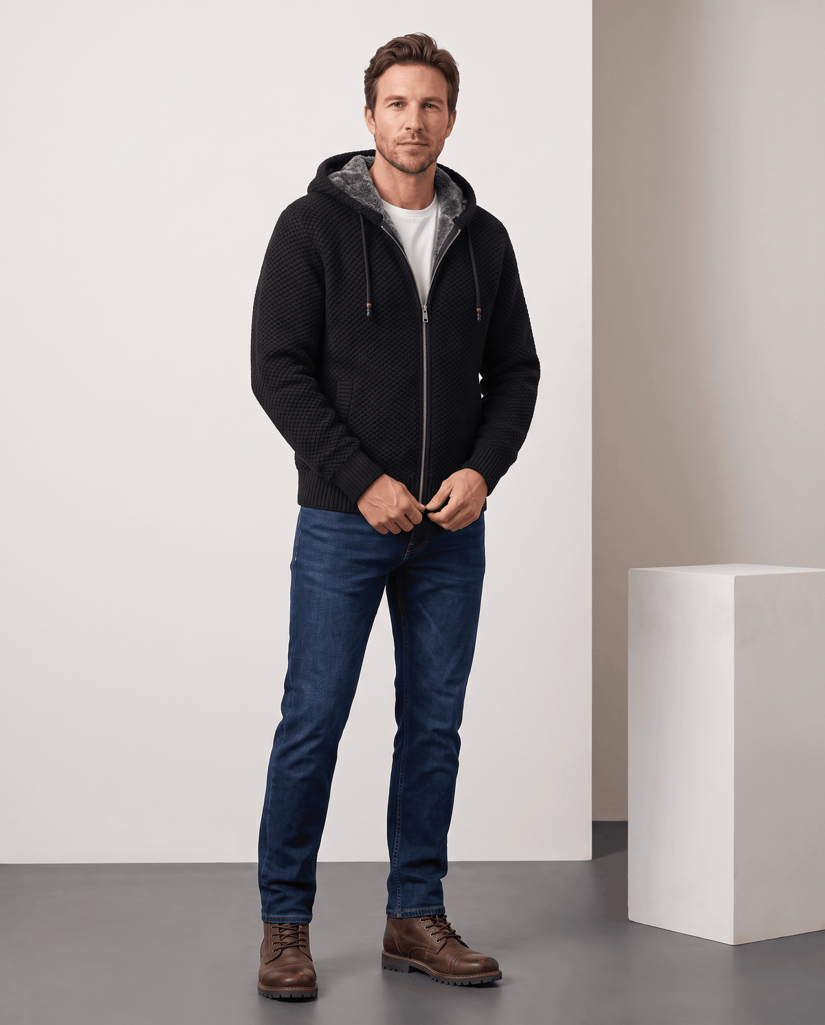 Full-length view of a man in a black zip hoodie, blue jeans and brown boots