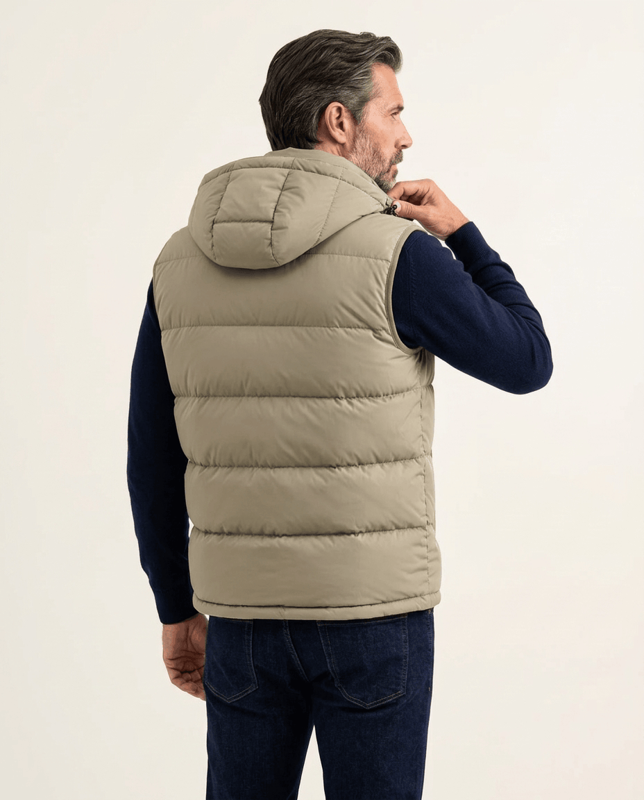 Back view of beige quilted vest with attached hood, worn over a navy sweater