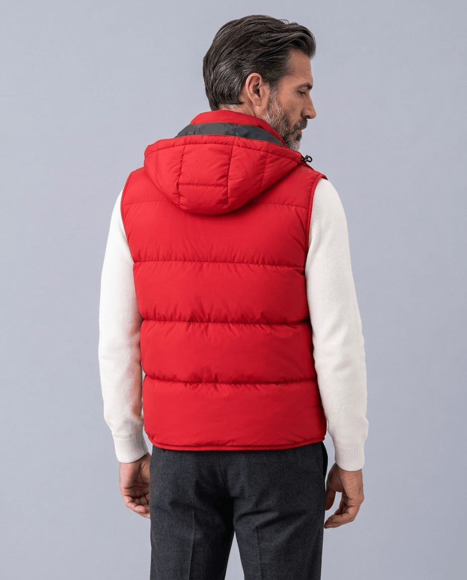 Back view of red quilted vest with attached hood, worn over a white sweater