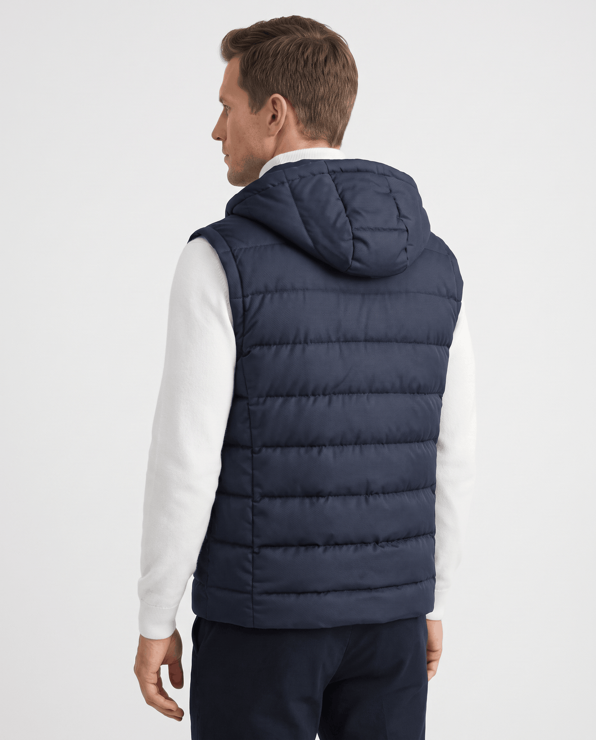 Back view of navy hooded quilted vest with channel quilting over a white sweater