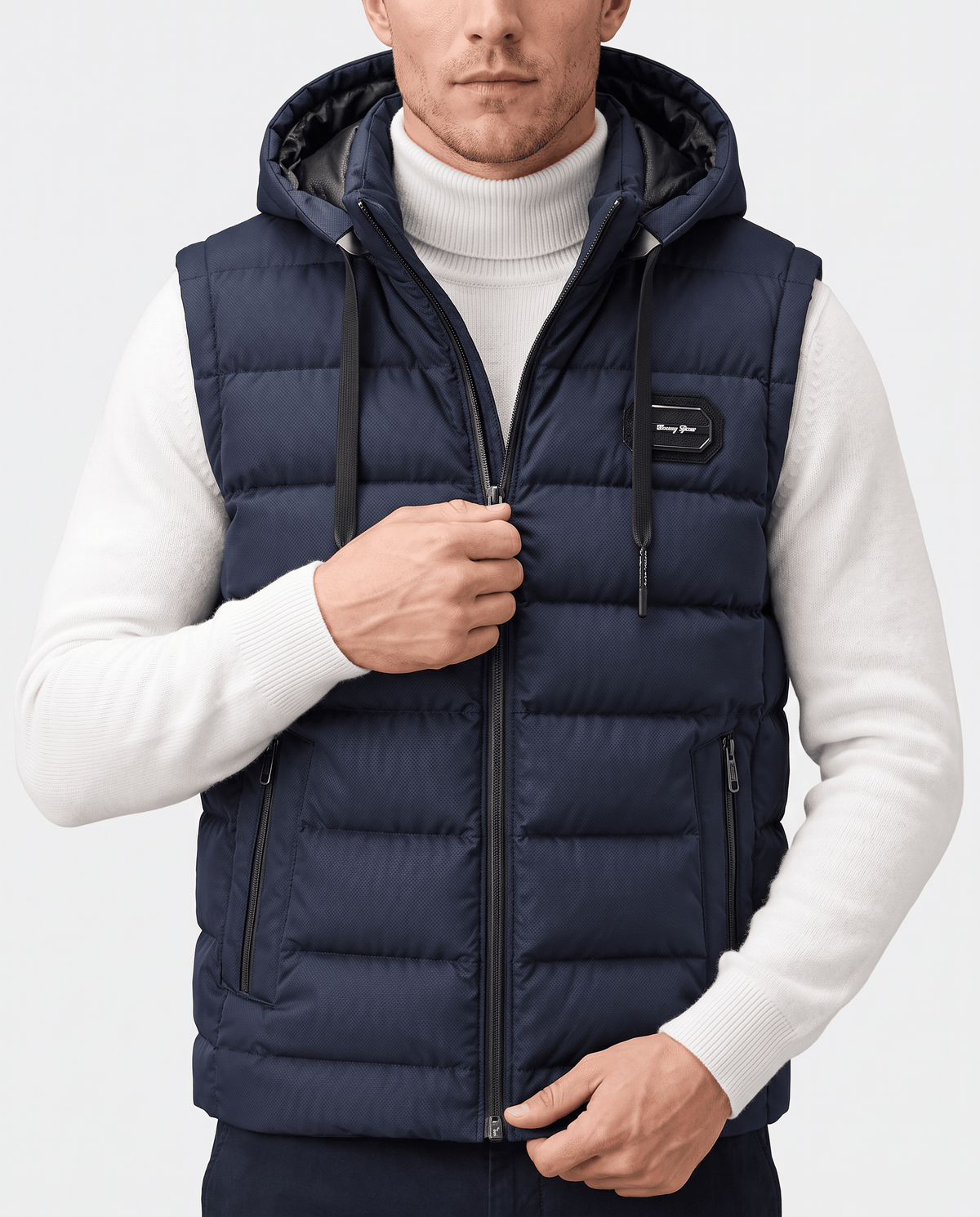 Navy hooded vest zipped to the collar over a white turtleneck, hand on the zip