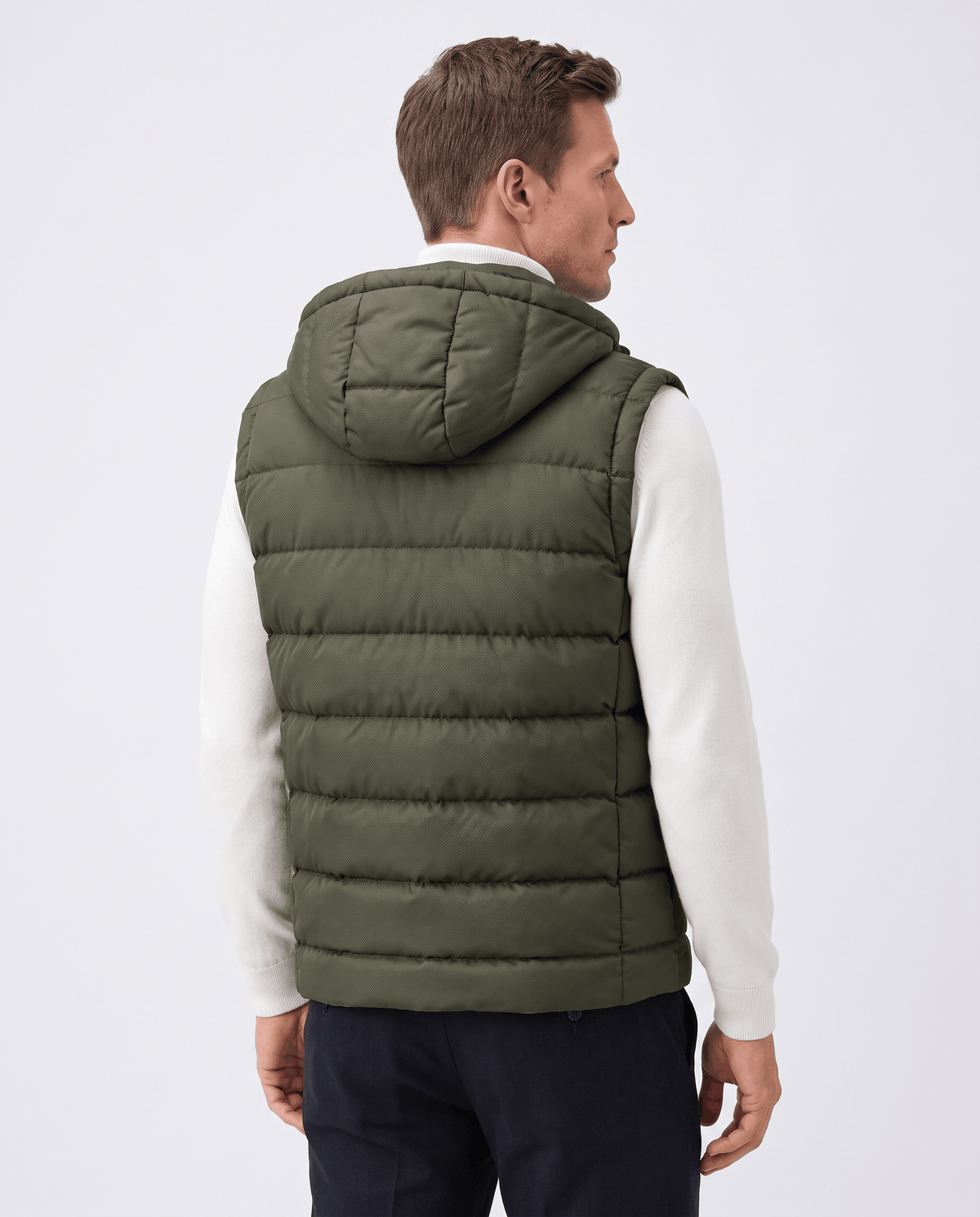 Back view of green hooded quilted vest with horizontal channel quilting over a white sweater