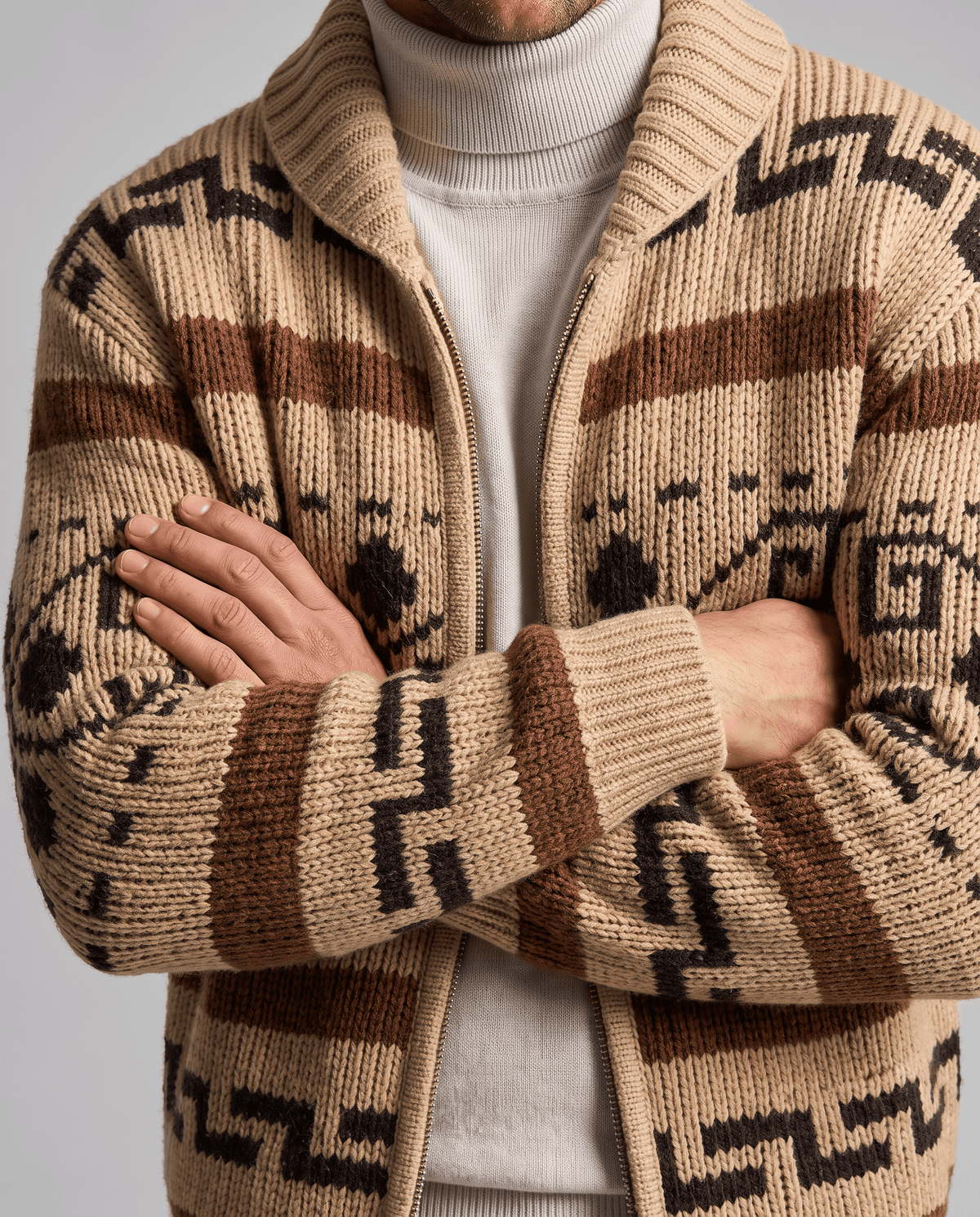 Khaki jacquard zip cardigan with arms crossed showing geometric pattern and ribbed cuffs