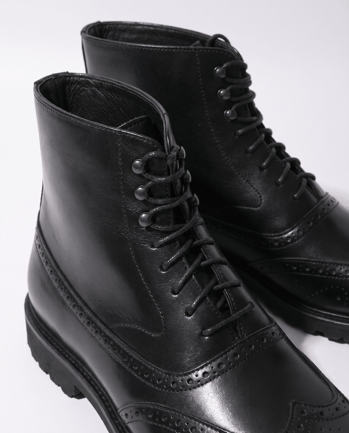 Close-up of black leather lace-up ankle boot showing the laces and smooth upper