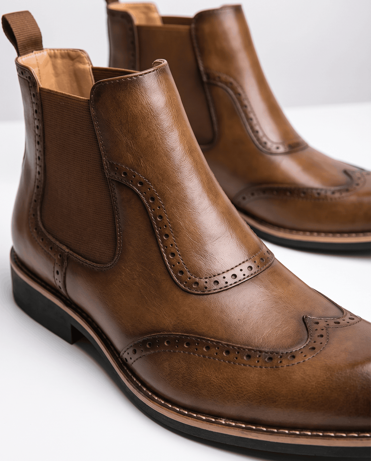 Close-up of tan leather brogue perforations and elastic side panel