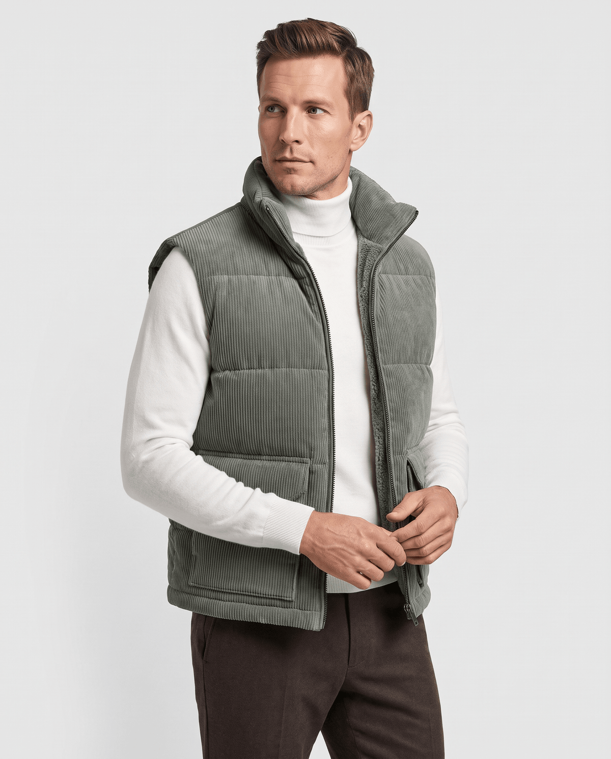 Green corduroy vest zipped over a white turtleneck with hands at the front pockets