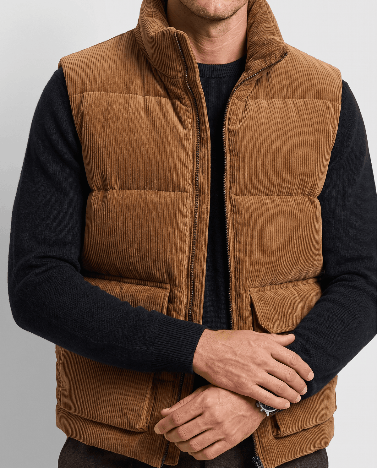 Brown corduroy vest with quilted panels and flap pockets, hands resting on the pockets