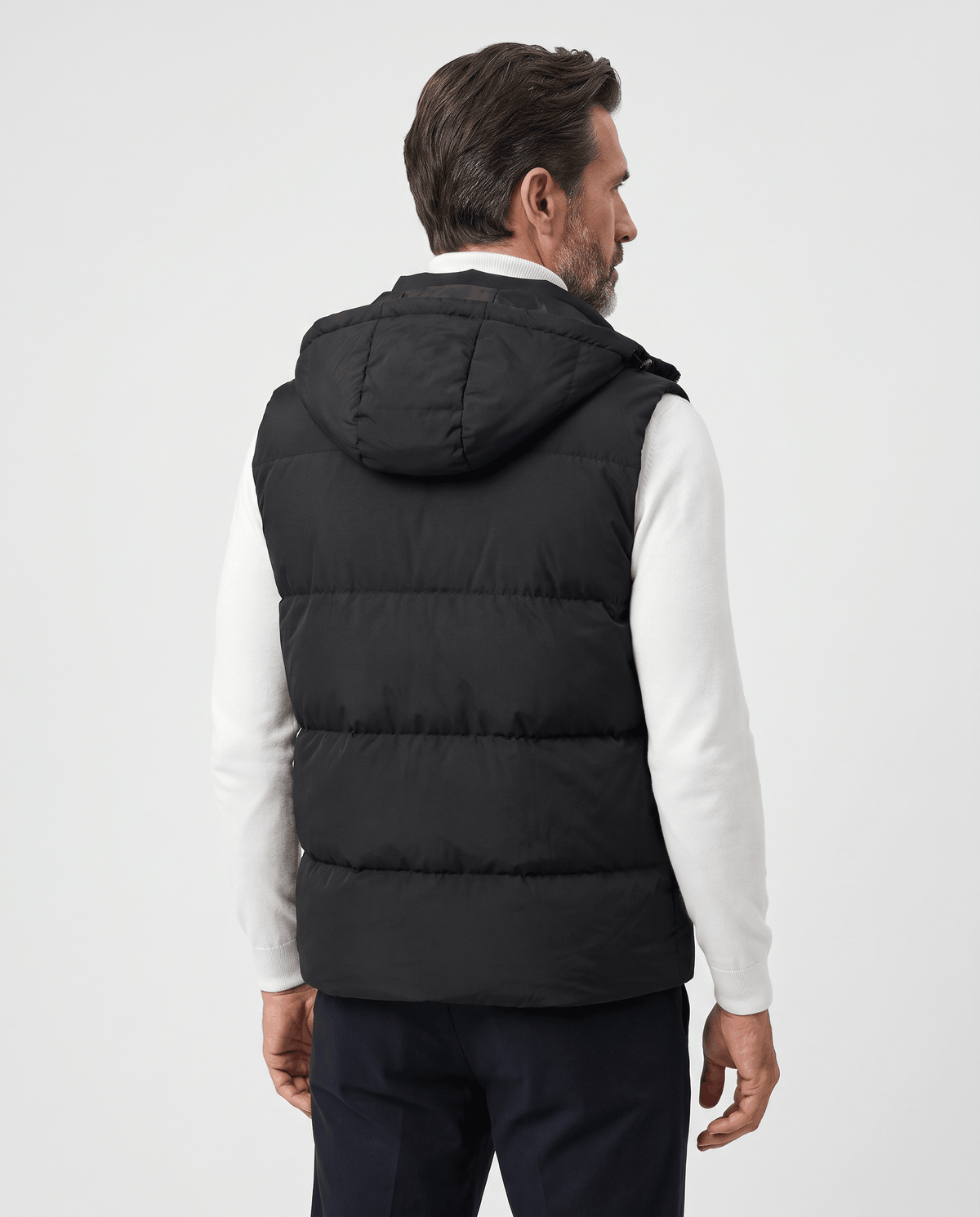 Back view of black padded hooded vest worn over a white sweater