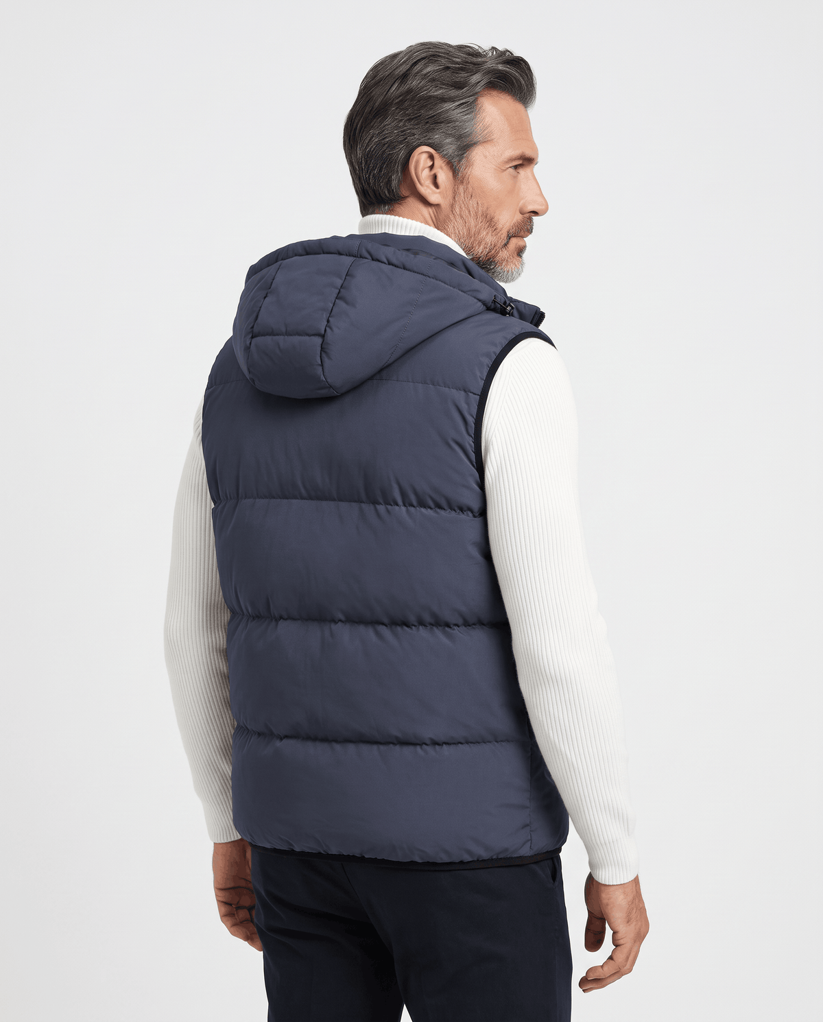 Back view of blue-gray padded hooded vest worn over a white sweater