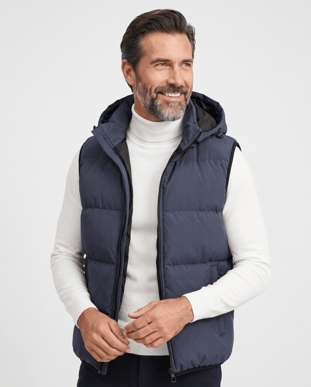Men's blue-gray padded hooded vest worn over a white turtleneck