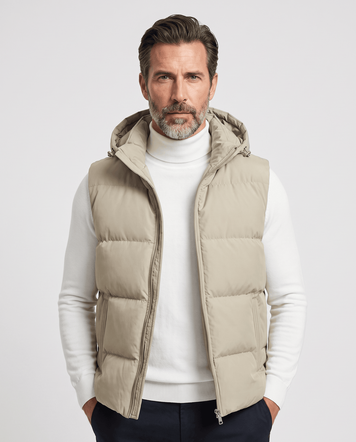Men's khaki padded hooded vest worn over a white turtleneck