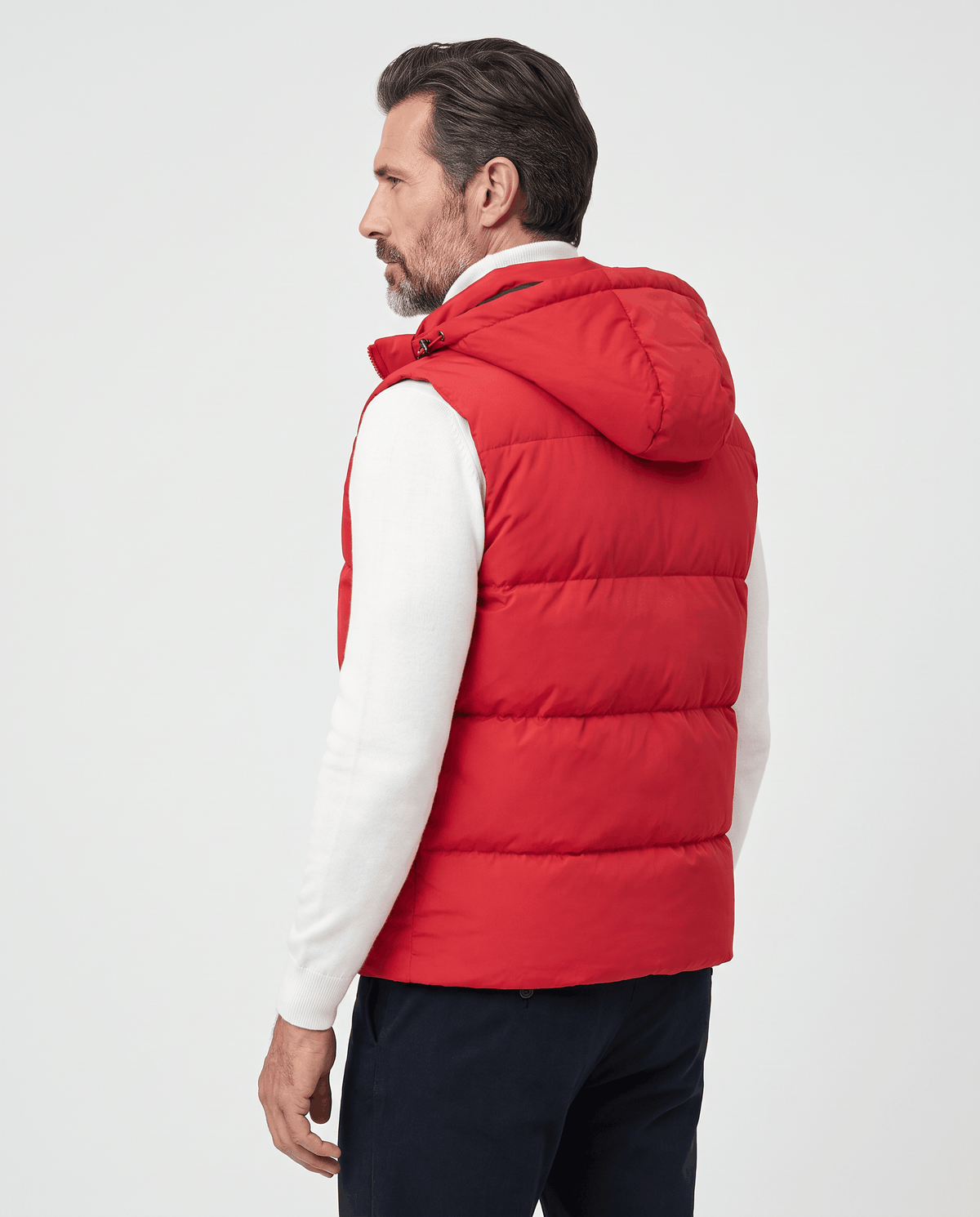 Back view of red padded hooded vest worn over a white sweater