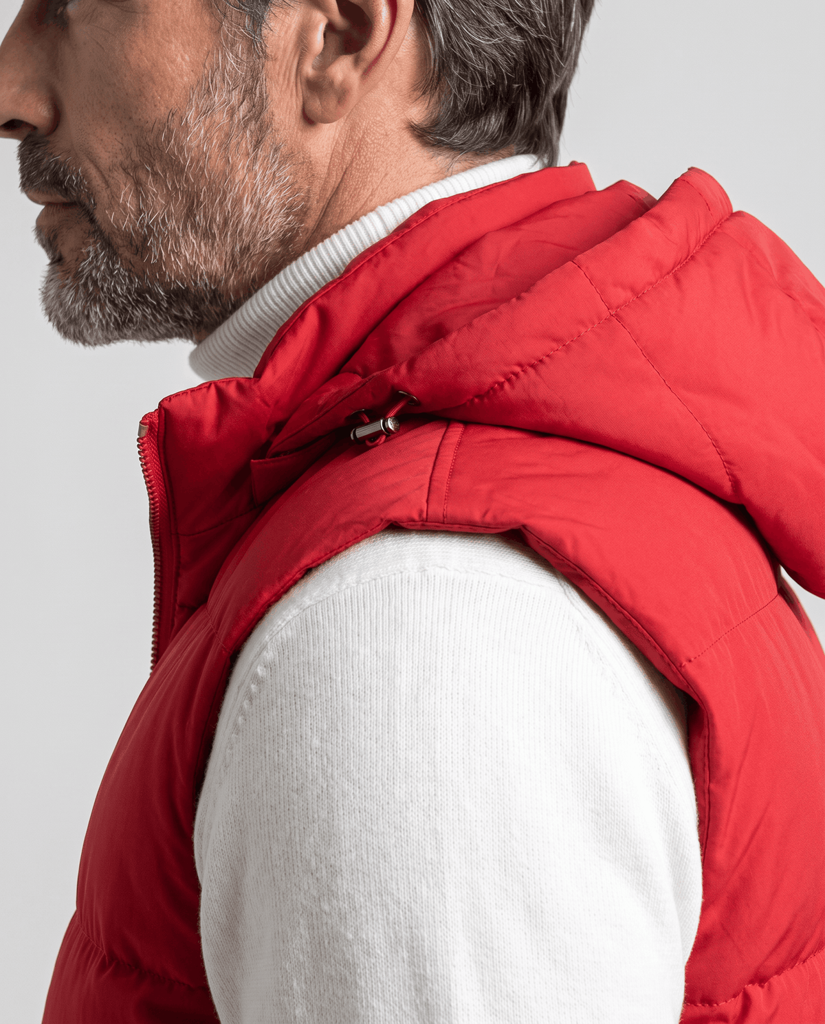 Side view of red padded vest hood and sleeveless armhole
