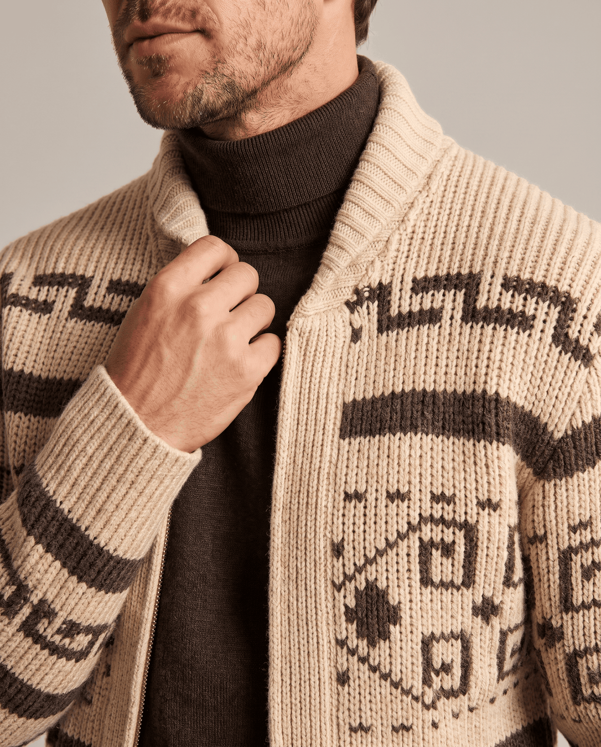 Khaki shawl collar cardigan over a brown turtleneck, close view of geometric pattern