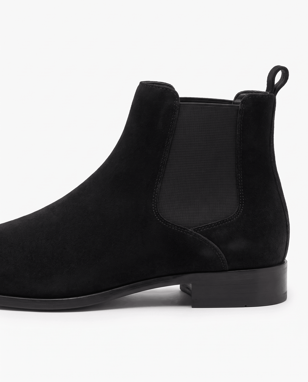 Side view of a black suede boot with heel pull tab and low stacked heel