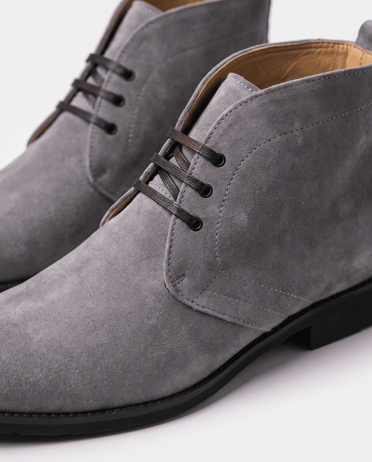 Close-up of gray suede chukka boot with short lace-up and tan lining.