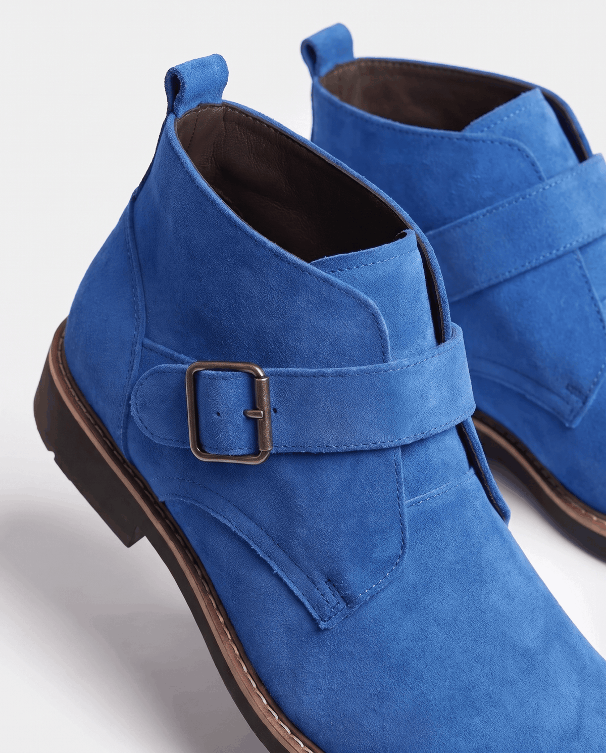 Close-up of a blue suede boot showing the buckle strap and heel pull tab