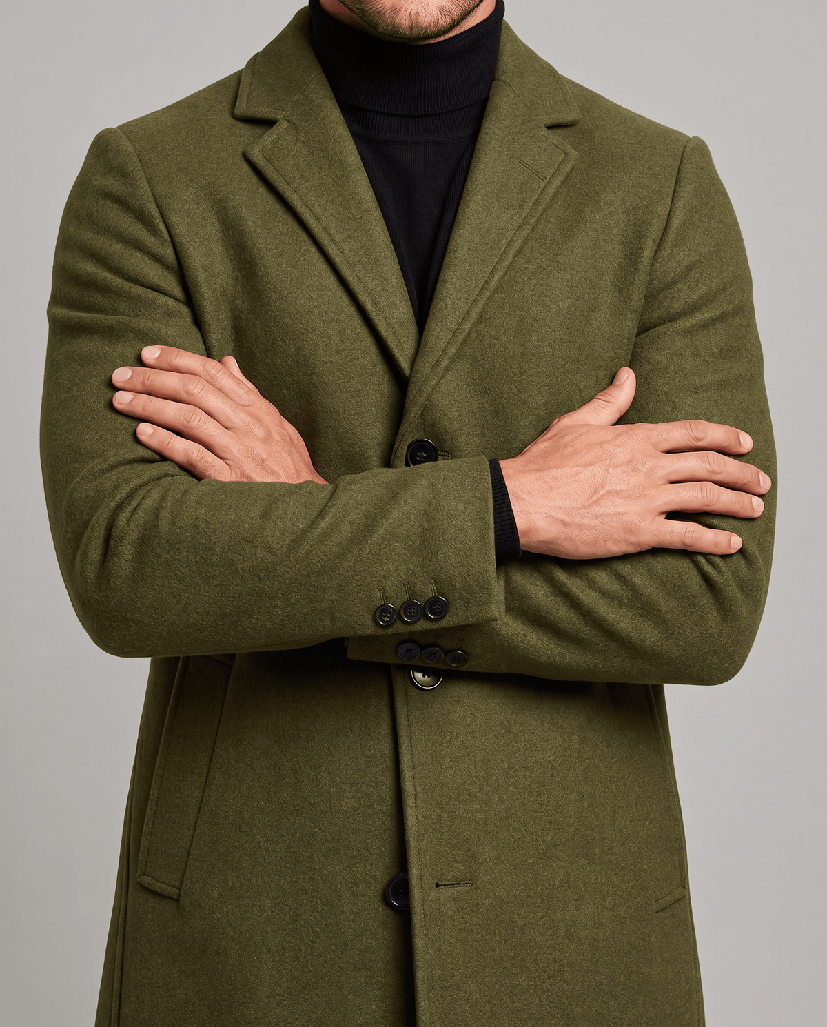 Army green overcoat front detail with notch lapel and button cuffs, worn with crossed arms