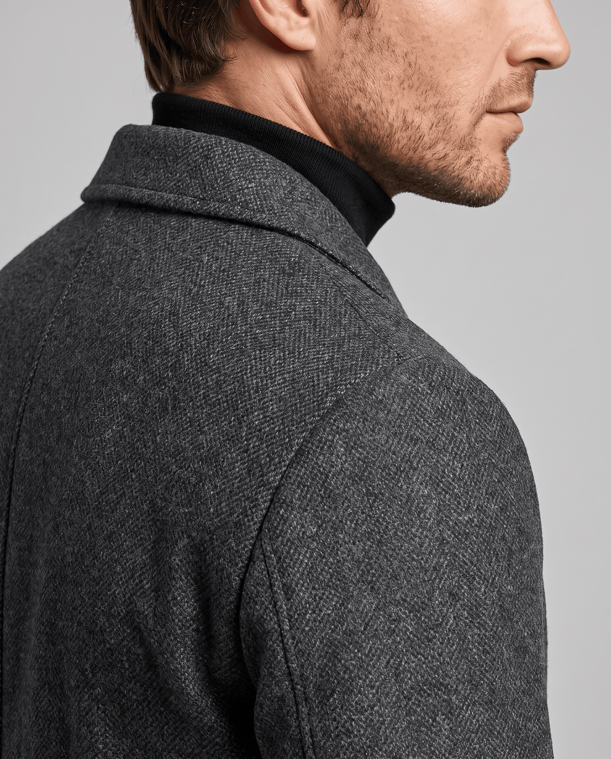Close-up of the dark gray overcoat's textured weave at the collar and shoulder