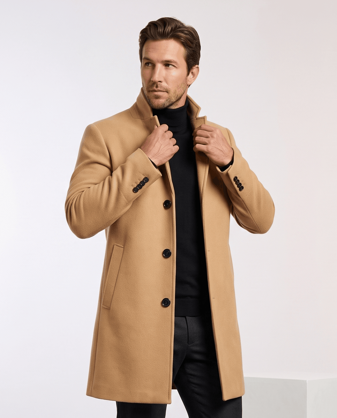 Khaki tailored overcoat buttoned over a black turtleneck, with one hand at the collar