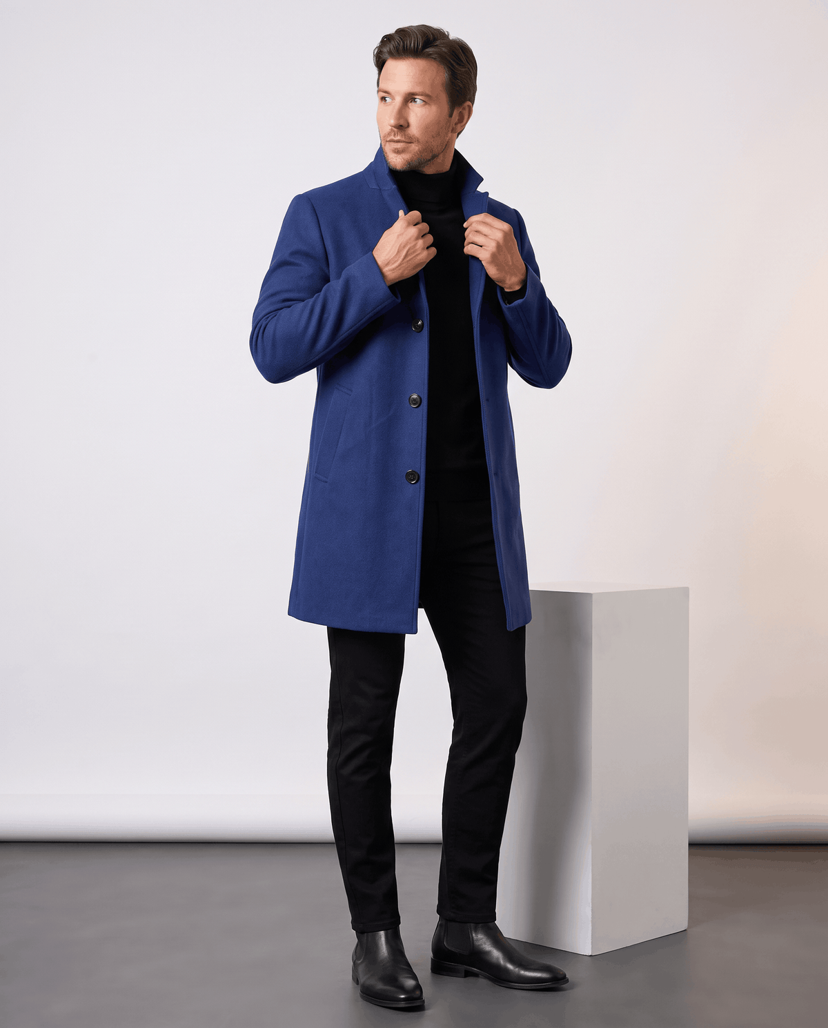 Full-length view of the blue overcoat worn with black trousers and dress shoes