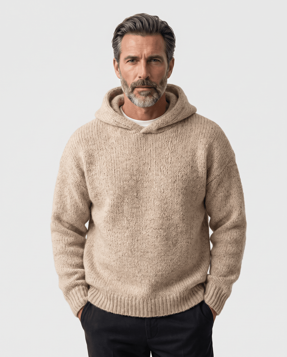 Man in a beige textured knit hooded sweater with hands in his pockets, front view