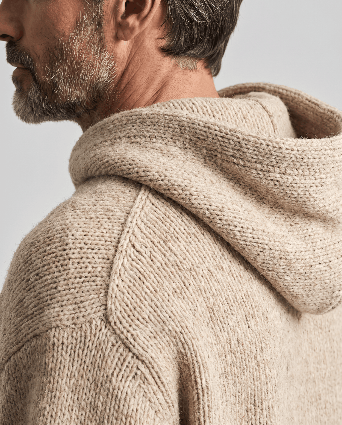 Side close-up of the beige hood and shoulder seam in a soft textured knit