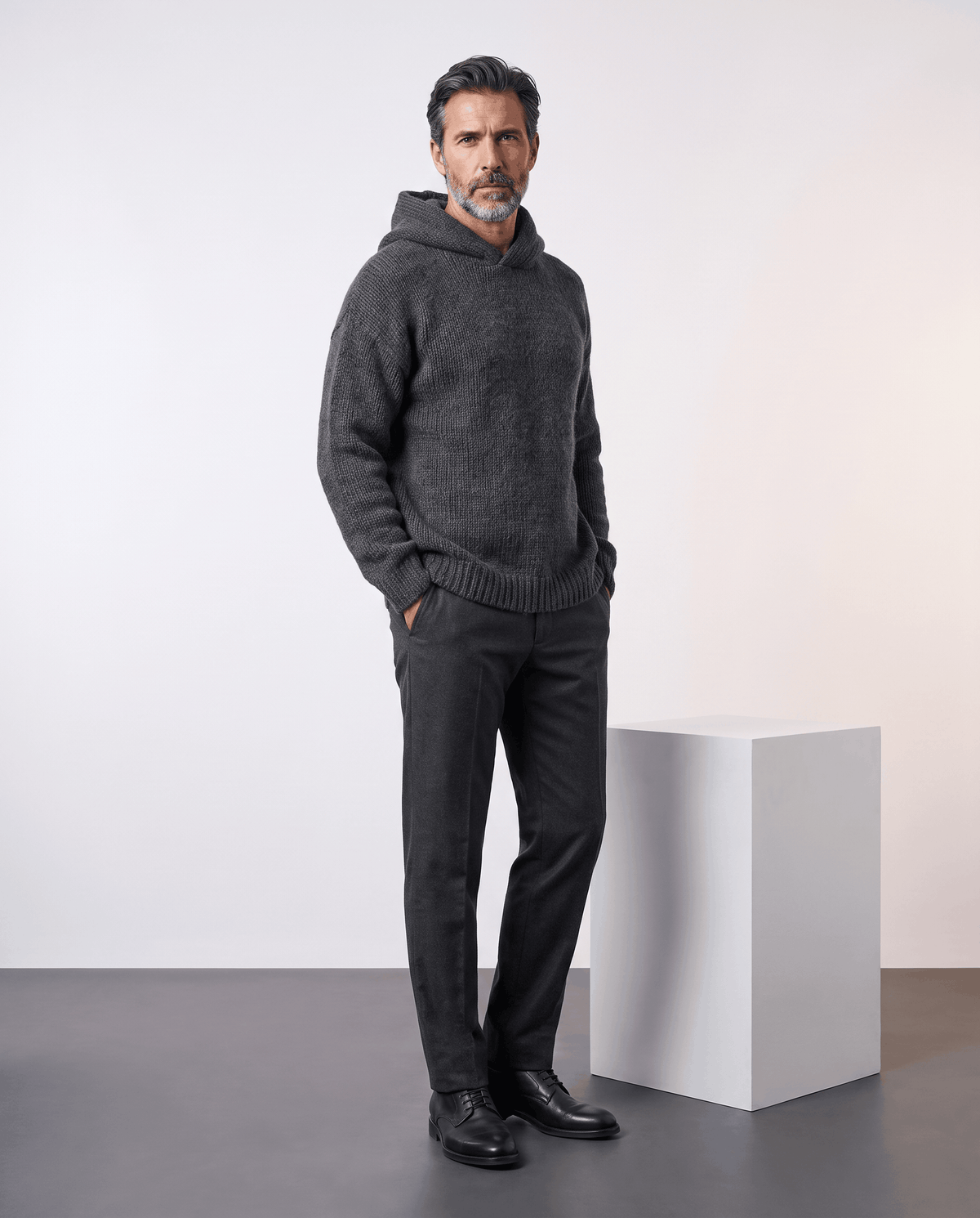 Full-length look: dark gray loose-fit knit with a hood, dark trousers and black shoes