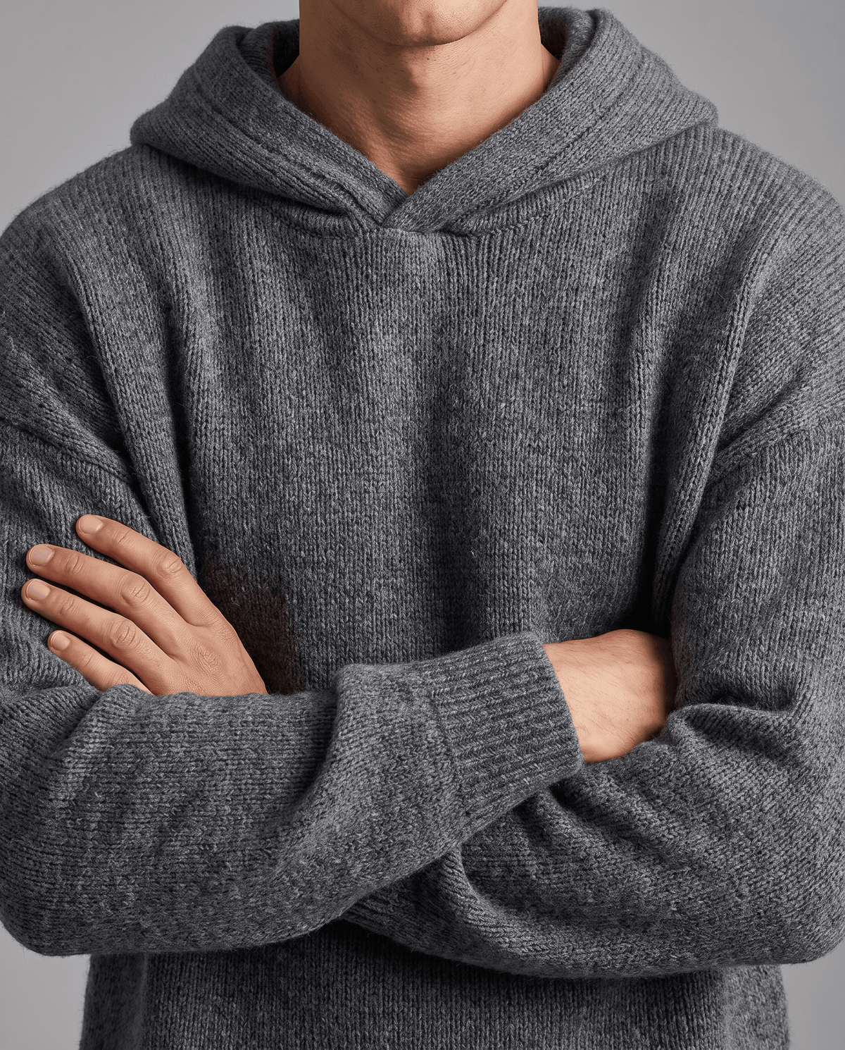 Close-up of a dark gray textured knit sweater with arms crossed over the front