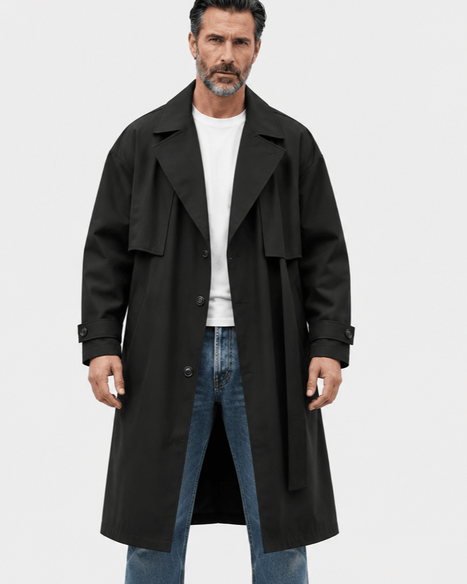Black longline coat worn open over a white tee and jeans with a belt hanging at the sides